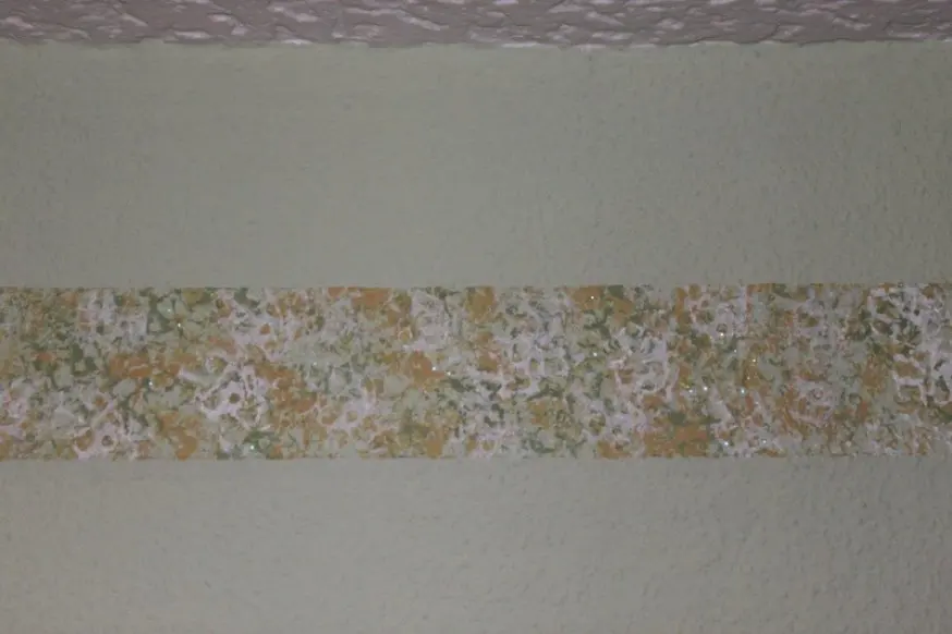Helle Wand mit einem waagerechten Band aus mehrfarbigem Buntsteinputz