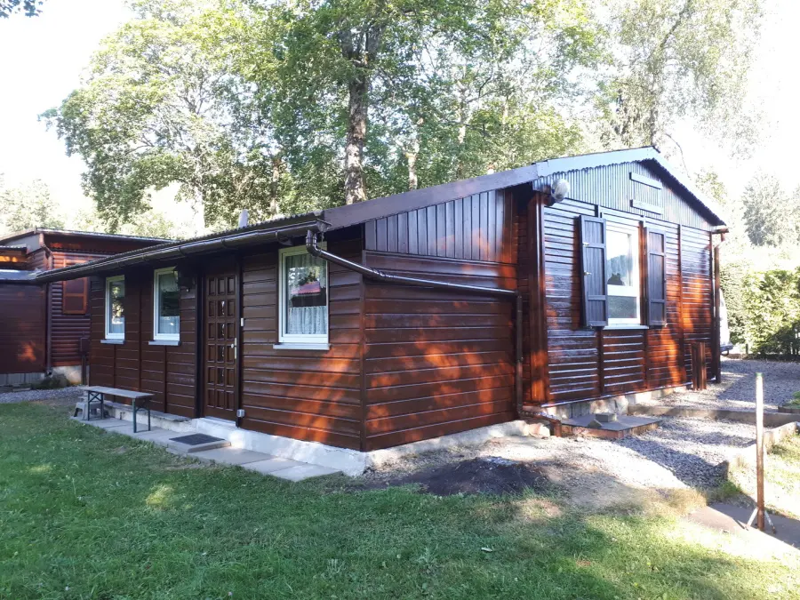Holzverkleidetes Ferienhaus mit dunkelbraun lasierter Fassade und Fensterläden