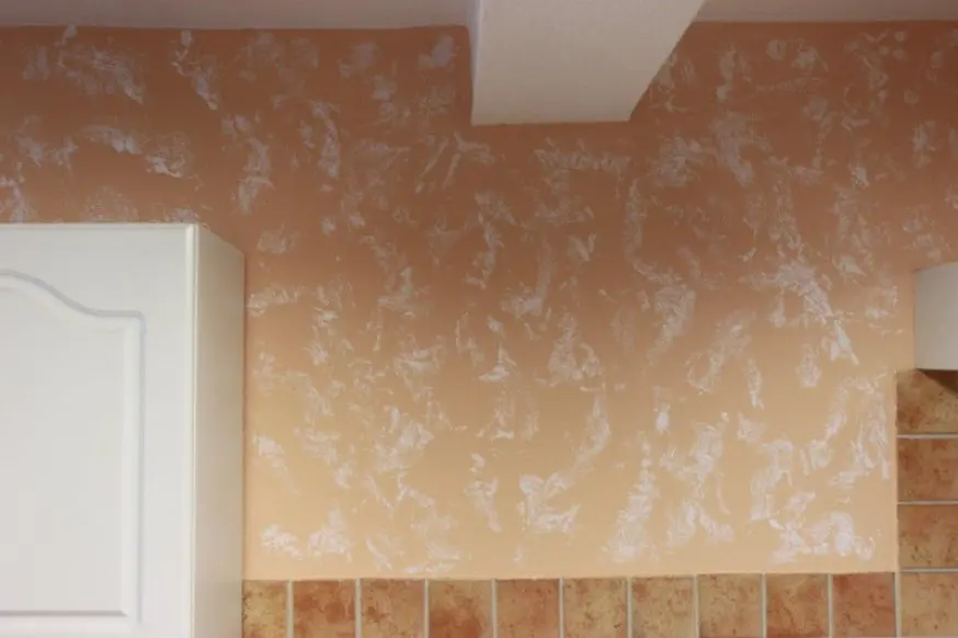 Küchenwand in Terrakotta-Ton mit weißer Tupftechnik über dem Fliesenspiegel