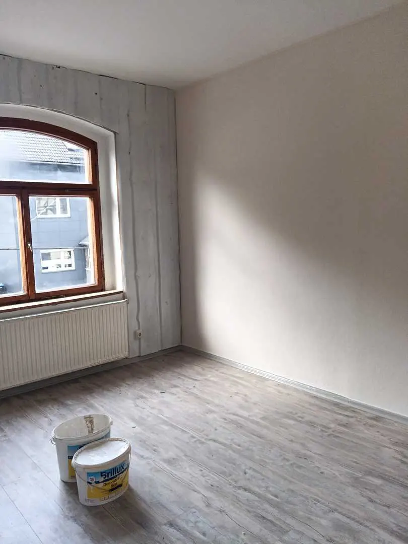 Leerer Raum mit frisch gespachtelter Wand, Rundbogenfenster und grauem Vinylboden