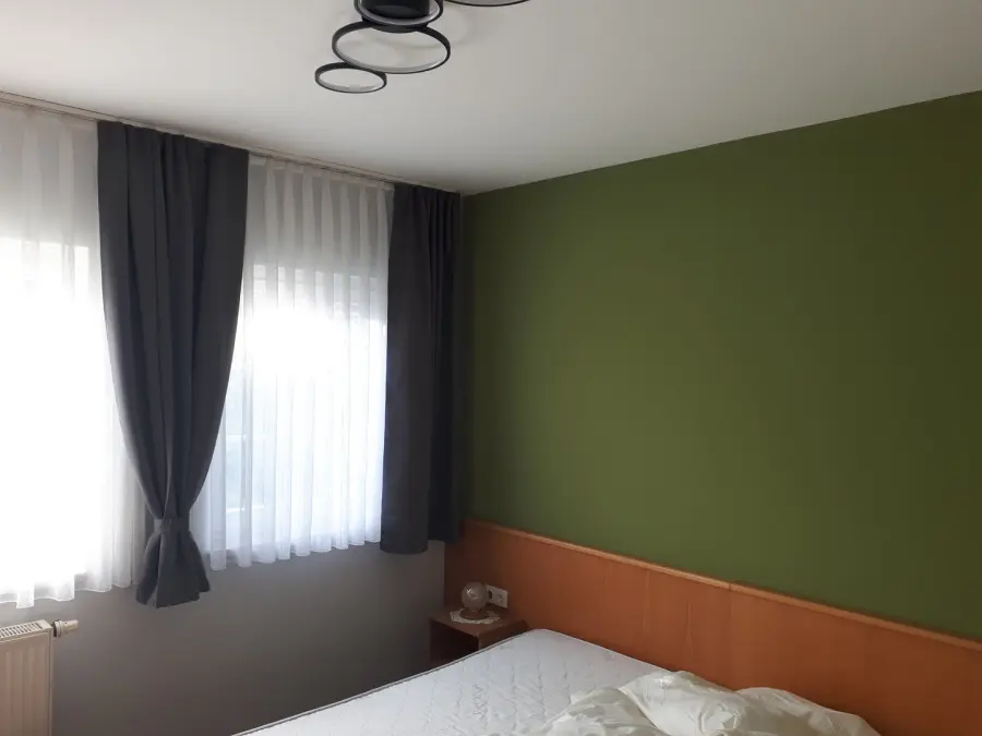 Schlafzimmer mit olivgrün gestrichener Akzentwand hinter dem Bett