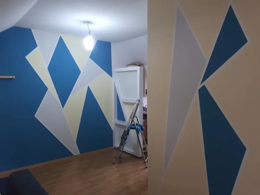Zimmer mit großflächiger geometrischer Wandgestaltung in Blau, Grau und Creme
